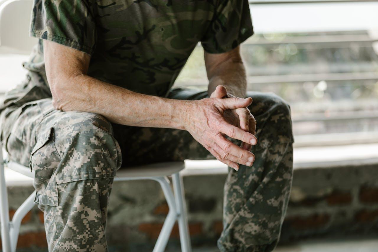 A veteran sitting with their hands upfront, thinking of the mental health challenges of veterans transitioning from active duty to civilian life.