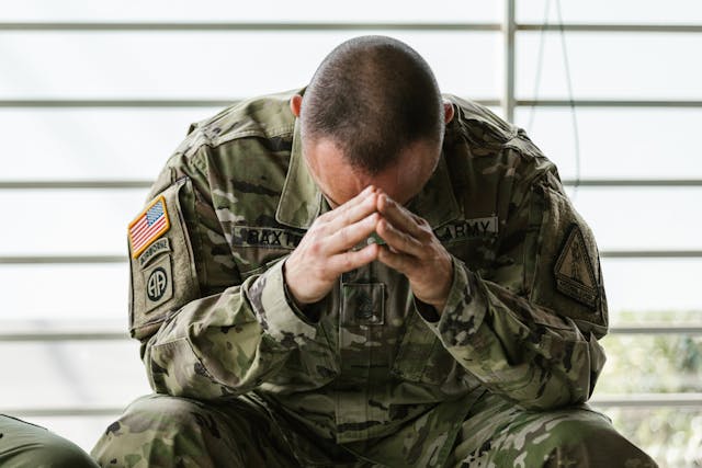 A stressed uniformed man holding his hands hears his head