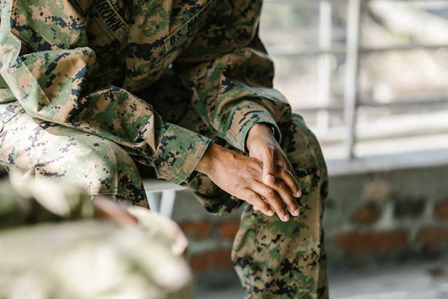 A man in a uniform sitting on a chair and holding his hands low